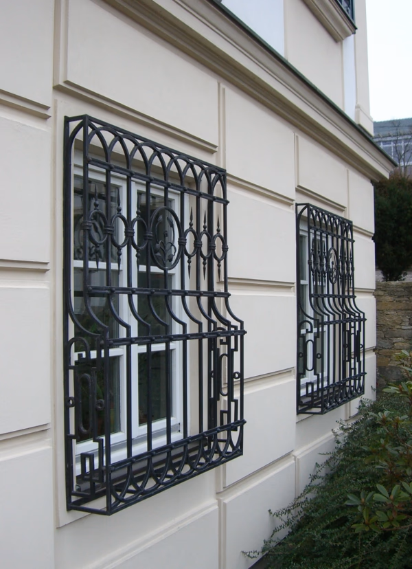 Dunkles Fenstergitter an einer hellen Fassade