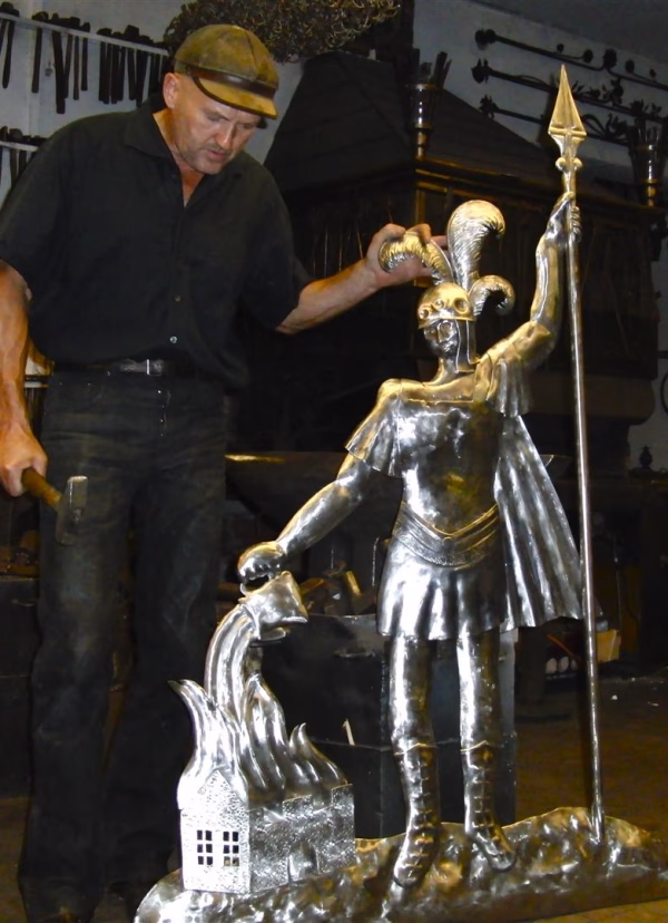 Große figürliche Metallskulptur in der Werkstatt; Person daneben